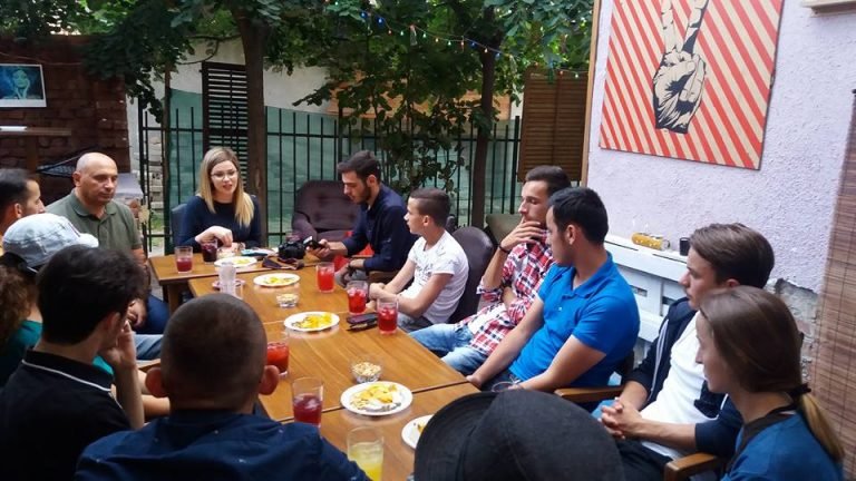 Diskutim rreth tavolinës në një mjedis me gjelbërim.