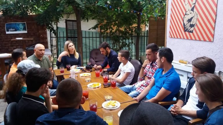 Diskutim rreth tavolinës në një mjedis me gjelbërim.